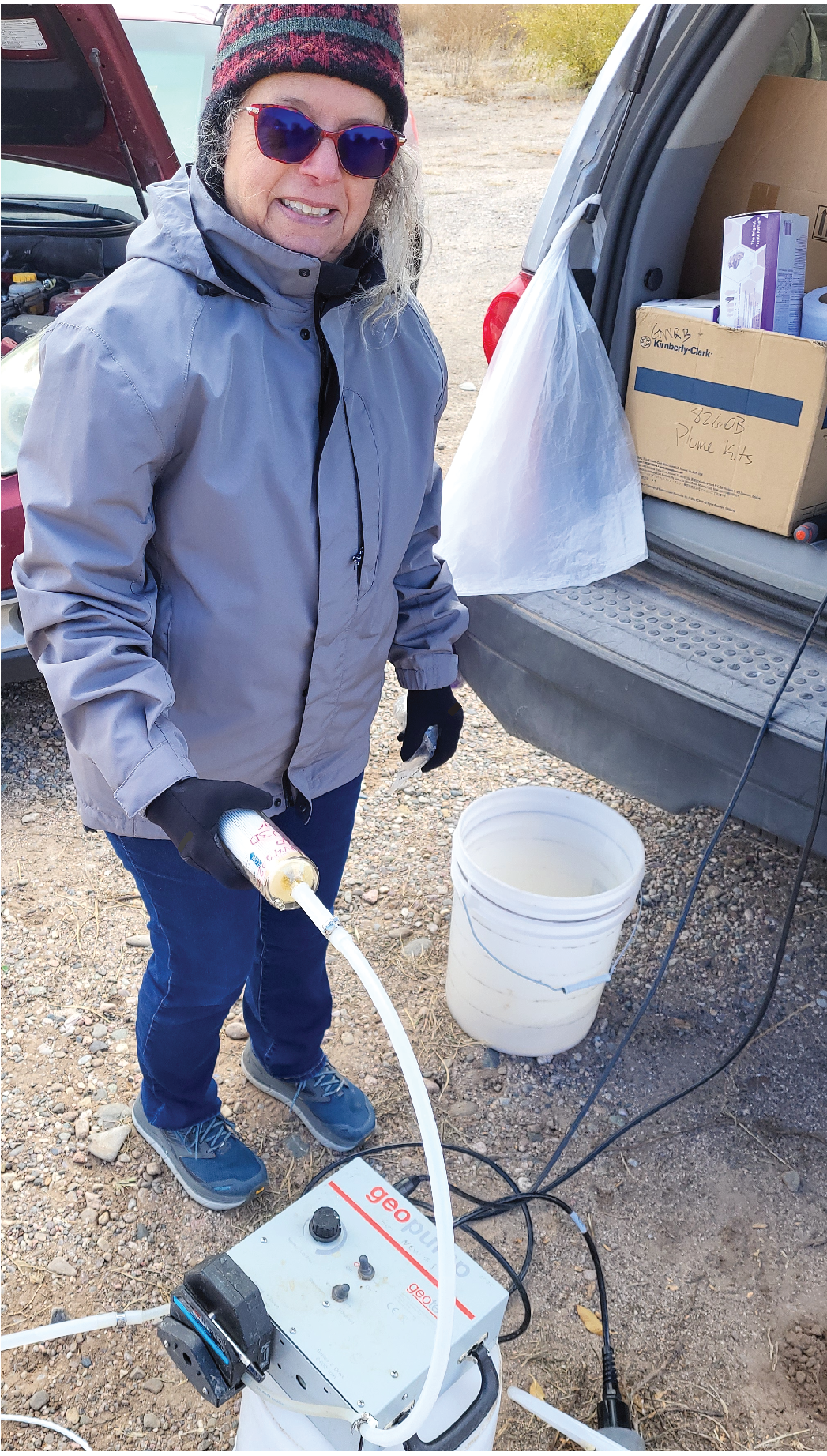 a person standing next to a car with a hose connected to a machine